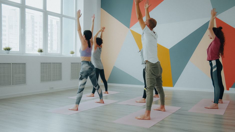 A teacher adjusting a student's pose during vinyasa flow